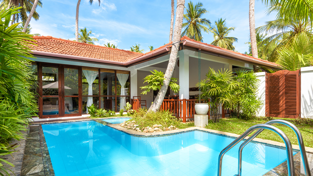 Luxury, small residential home with a swimming pool, surrounded by palm trees, photographed during a home inspection
